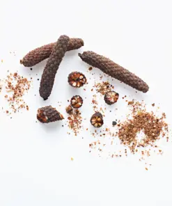Dried whole and crushed Javanese long pepper (Piper longum) on a white background, a raw material for high-piperine herbal extracts from an Indonesian B2B supplier.